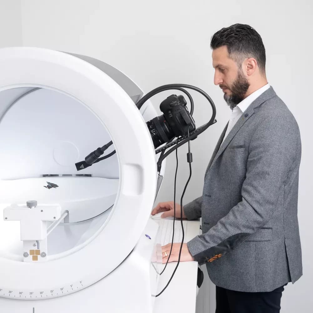 Hombre con traje operando un dispositivo fotográfico Orbitvu