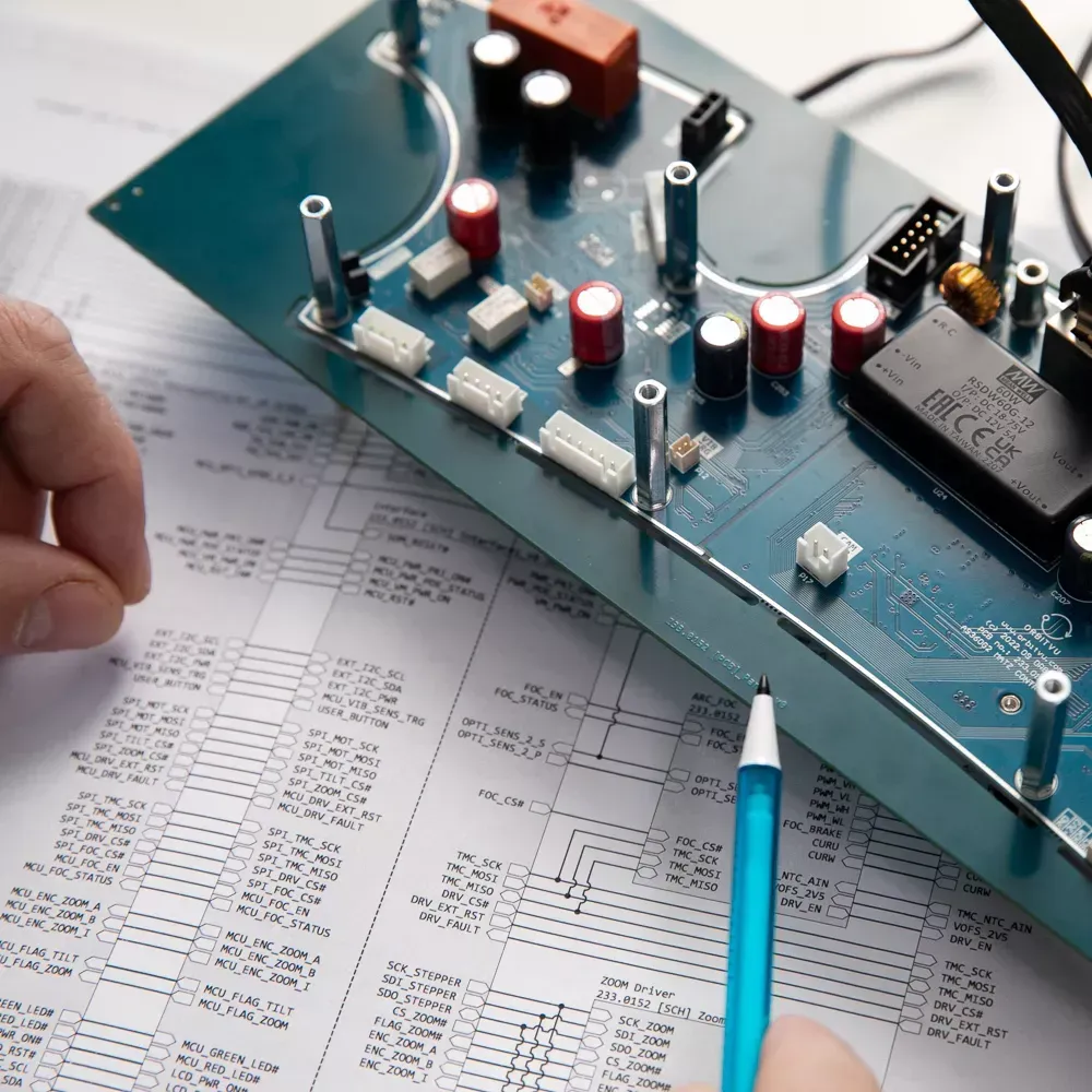 Ingeniero revisando una placa electrónica y un esquema técnico