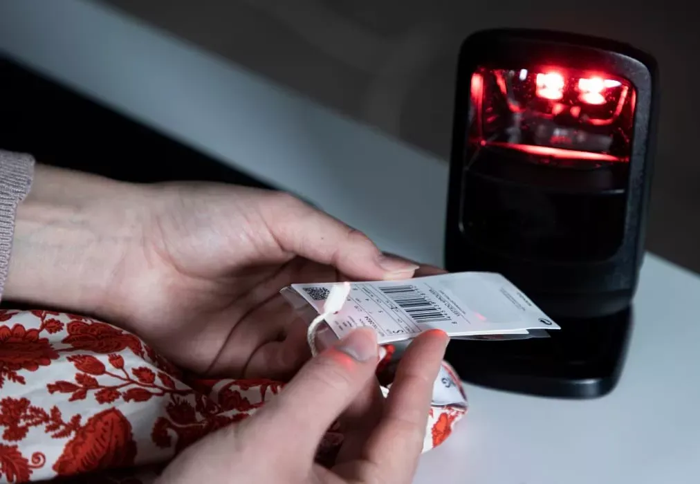Primer plano de manos escaneando la etiqueta de código de barras de una prenda para inventario
