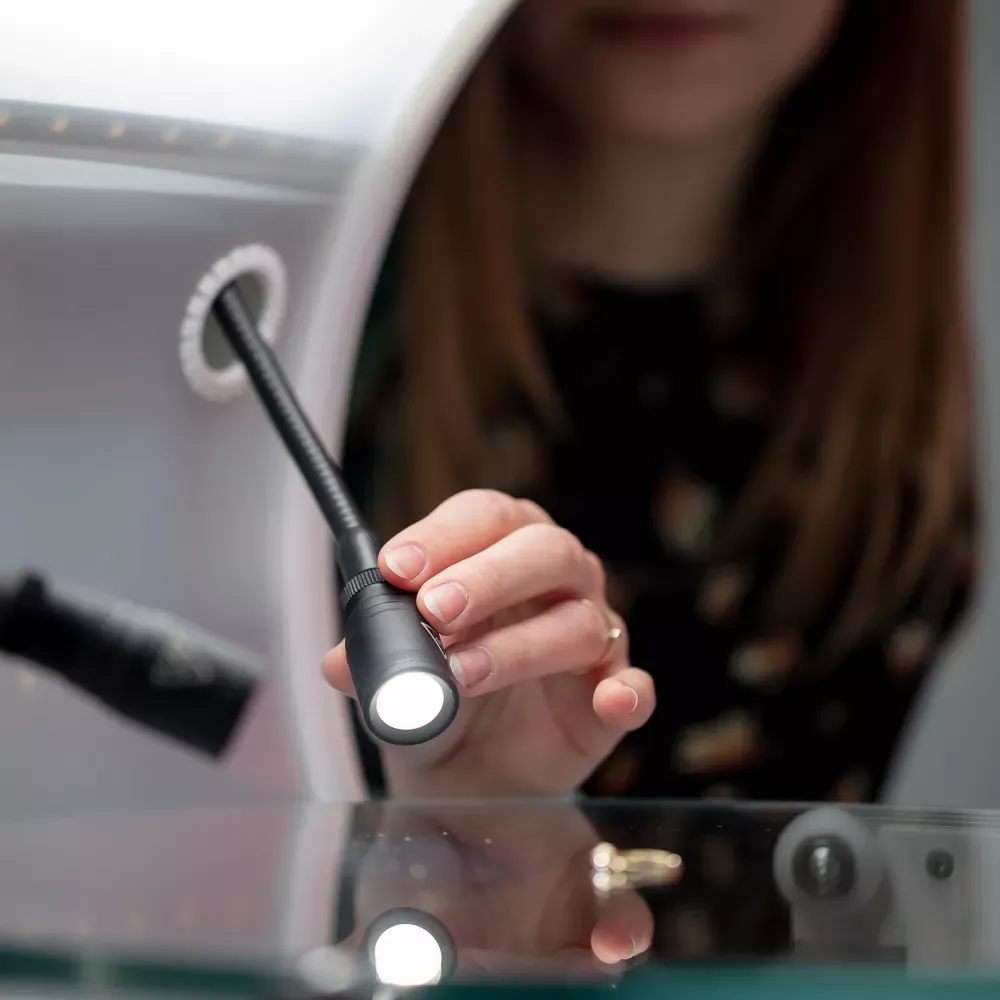 Mujer ajustando una luz LED en una configuración de fotografía de joyería