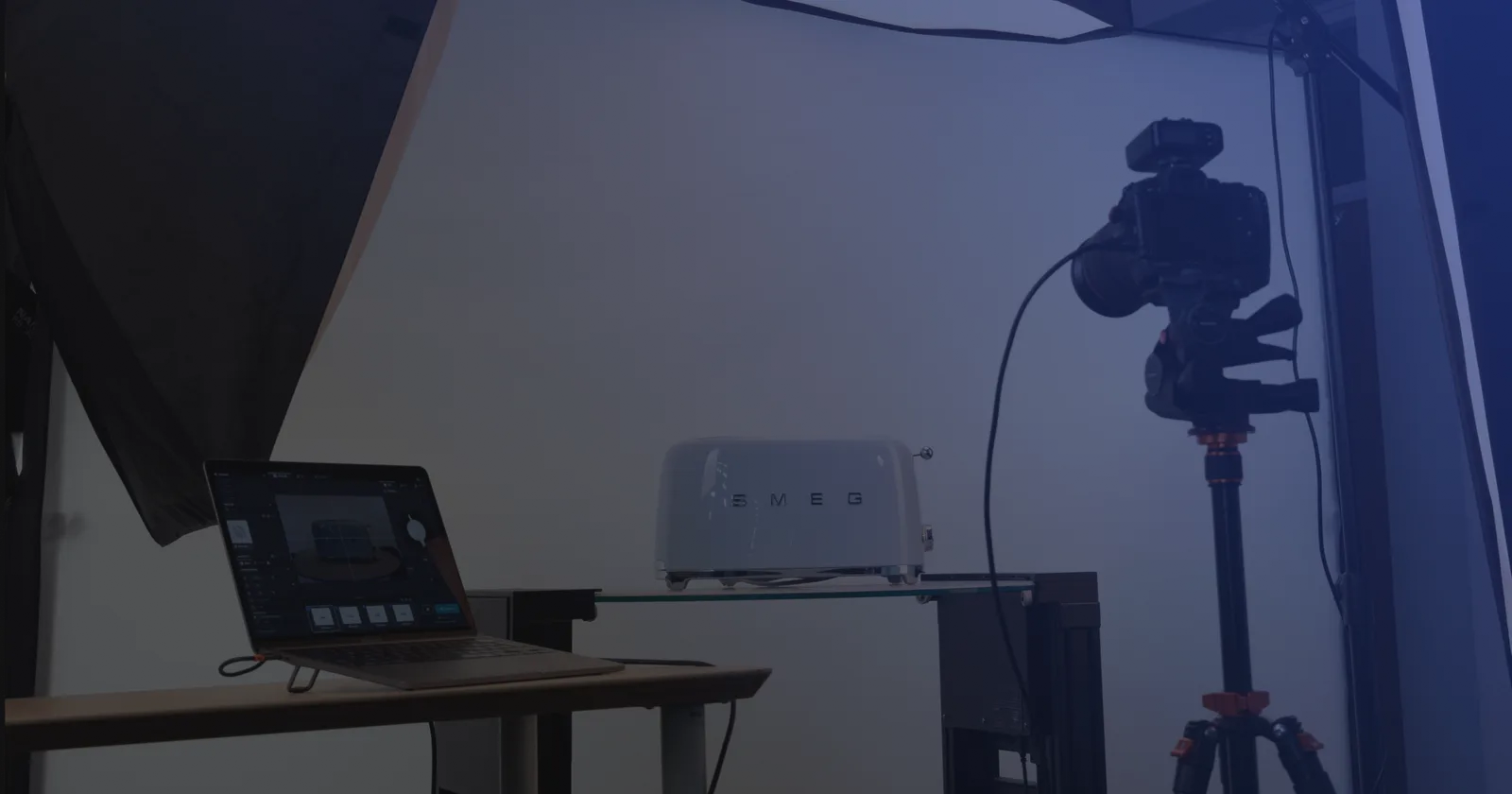 Set de fotografía de producto con tethering: un notebook con el software de captura junto a una cámara en trípode y un producto sobre una repisa de vidrio
