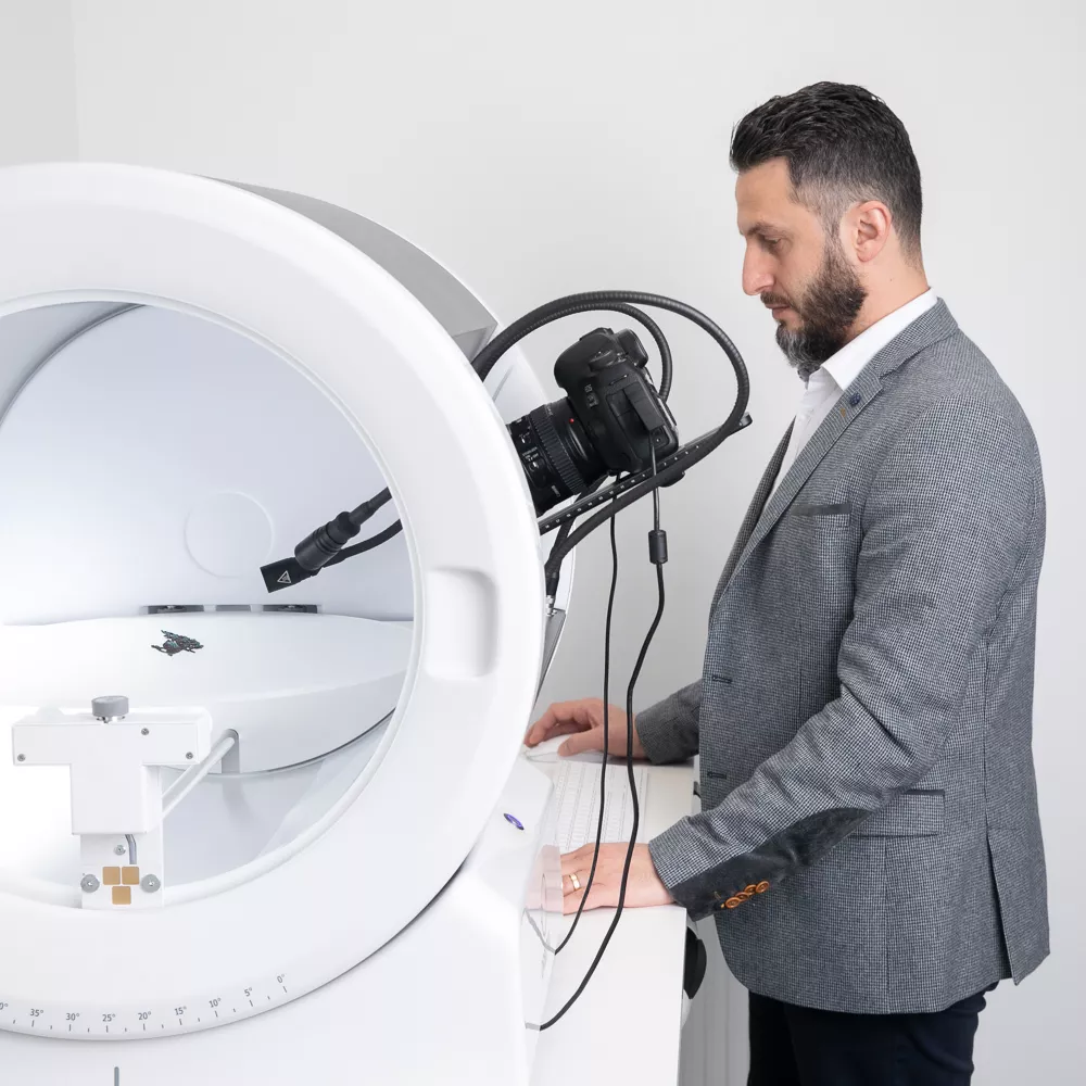 Hombre con traje operando un dispositivo fotográfico Orbitvu
