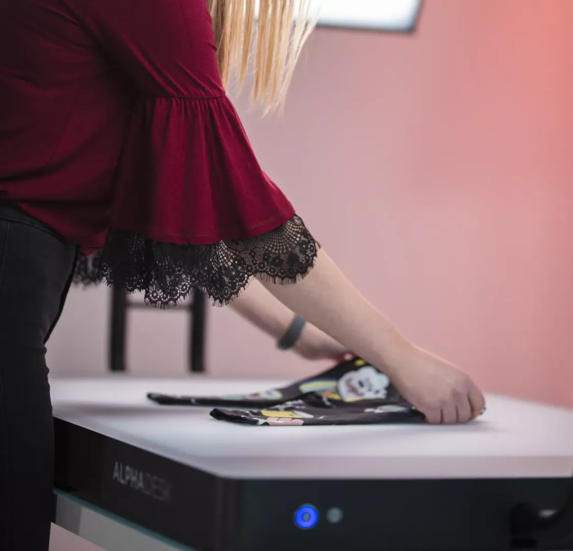 Mujer doblando ropa infantil sobre una mesa blanca con Alphadesk